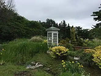 Photograph of a white telephone booth in a garden