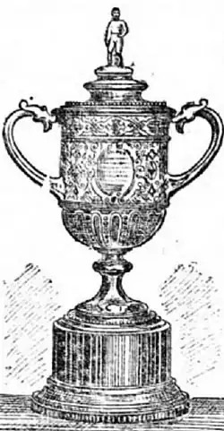 A trophy, silver in colour and topped by a figure of a footballer, on an ebony plinth