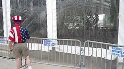 A man in a red, white and blue outfit peers into a canvas tent.