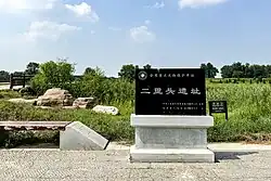A Chinese sign in a grassy park, marking the area as the Erlitou National Archaeological Site Park