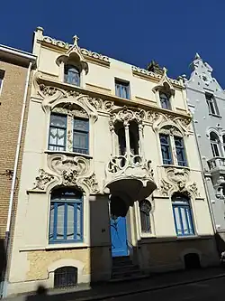 Mix of Art Nouveau and Gothic Revival – Rue Gustave-Lemaire no. 51 in Dunkirk, France, with pointed arched-dormer windows and balcony loggia, unknown architect, decorated with sculptures by Maurice Ringot (1903–1910)[176]