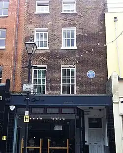 exterior of darked bricked house, with blue plaque on front wall