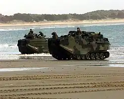 Two U.S. Marine Corps Assault Amphibious Vehicles emerge from the surf onto the sand of Freshwater Beach, Australia