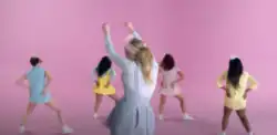 Four women twerking and one standing still in front of pastel-colored pink backdrop.