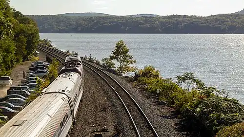A passenger train on a riverside rail line