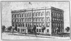 Illustration of a four story building, thirteen bays wide. There is a covered portico in front of the main entrance.