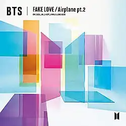 Cover of BTS' Fake Love / Airplane pt. 2 Japanese Single. The BTS logo, two trapezoids with the flat end facing each other, are in the middle, made out of pink (left) and blue (right) tinted glass. Various rectangles of tinted glass, in pink, purple, orange, and black, surround the logo. A black version of the logo is on the bottom right, and the worst "BTS Fake Love / Airplane pt. 2" is written at the top.