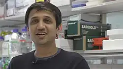 Tanmay Bharat stood in a lab space at the MRC Laboratory of Molecular Biology