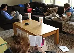 Four people sitting around a coffee table reading scripture