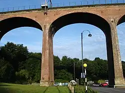 A large railway viaduct made from red bricks, topped by railings and electric pylons