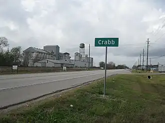 Crabb road sign on FM 762 looking west with disused grain elevator on left and businesses on the right