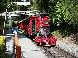 A red steam locomotive with a 2-4-0 wheel arrangement and its tender