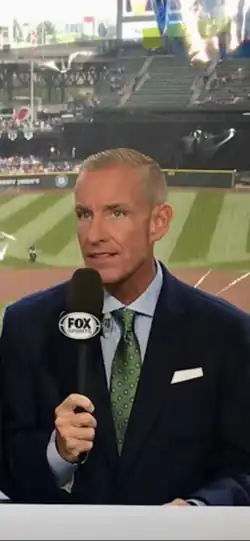 Dan McLaughlin in broadcast booth holding microphone