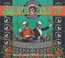 Two skeletons in formal attire operate mechanical devices. In the foreground is the Wall of Sound concert sound system, and roses.