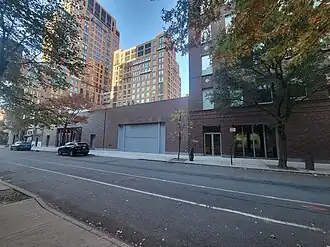 two one-story brick buildings next to a taller building all constructed of brick on a street lined with trees
