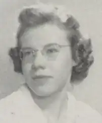 A young white woman with light hair in a set style, wearing glasses
