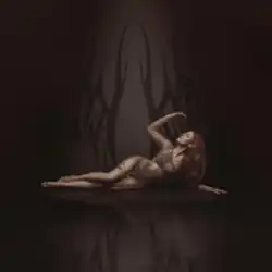 Dotter lying on her side wearing a see-through string dress in front of a patterned background