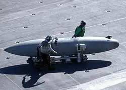 A 330-US-gallon-capacity (1,200&nbsp;L) Sargent Fletcher drop tank being moved across the flight deck of an aircraft carrier