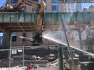 Water being sprayed onto an excavator demolishing an elevated railway viaduct