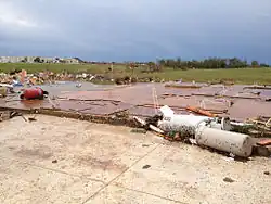 EF5 damage example--Well-built and well-anchored homes are taken off their foundations and they go into the air before obliteration. The wreckage of those homes is flung for miles and those foundations are swept completely clean. Large, steel-reinforced structures such as schools are completely leveled. Low-lying grass and vegetation are shredded from the ground. Trees are completely debarked and snapped. Very little recognizable structural debris is generated with most materials reduced to a coarse mix of small, granular particles and dispersed. Large, multiple-ton steel frame vehicles and farm equipment are often mangled beyond recognition and tossed miles away or reduced entirely to unrecognizable parts. Tall buildings collapse or have severe structural deformations. The official description of this damage highlights the extreme nature of the destruction, noting that "incredible phenomena can and will occur".