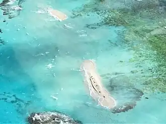island almost completely submerged, with only small sand remnants and reef structures visible underwater