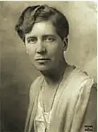 B&W portrait photo of a middle-aged white woman with her hair in an up-do, wearing a pale blouse and jacket