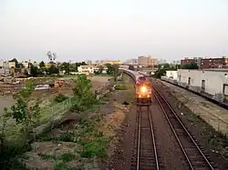 A train passing a cleared parcel in an urban area