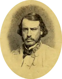 Sepia toned oval photo shows a mustachioed man looking hard at the camera. He wears a light-colored uniform with the stars of a general on his collar.