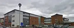 Modern red brick and plaster buildings with a car park in the foreground