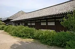 Long wooden building with white walls.