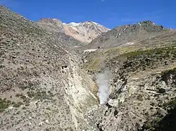 Steam plume emanates from the bottom of a narrow valley in the mountains