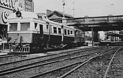 Black and white photograph of the bridge, with train and tracks in the foreground