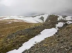 The prospecting trench on the summit of Hart Side, partly filled with snow, with Green Side and Stybarrow Dodd in the distance