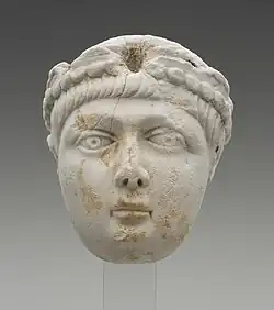 A Miniature portrait head of a young boy with a full face and short, straight hair. He wears a pearl-edged diadem, which identifies this head as portrait of an Emperor. The head greatly resembles depictions of the Theodosian princes. This marks the identification of the head to be either Honorius, Arcadius, or Valentinian II.