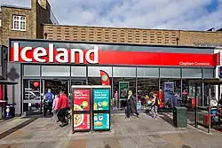 A high street storefront with large glass sections having buildings to either side
