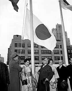 A group of men and women watching a flag being raised.