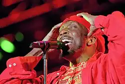 A man in red clothing singing into a microphone.