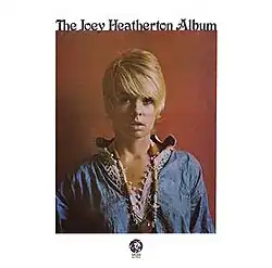 A woman, with blonde short hair cut, wearing a blue tunic, facing forward. The text reads "The Joey Heatherton Album".