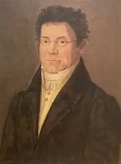 middle-aged white man, clean shave, bespectacled, facing the painter