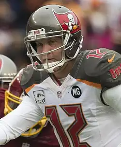A zoomed-in photo of a helmeted football player in a white #12 jersey