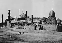 Black and white photograph of a walled city in the desert, showing domes and minarets.