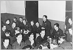 black and white photography of a man at a dinner table giving a speech to a room full of seated men