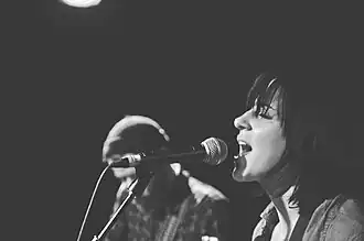 Stevenson singing into a microphone, with another performer in the background.