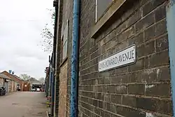 Lewis Howard Avenue Street Sign with the Road in the Background (2018)