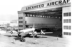 An aircraft being positioned outside a large hangar