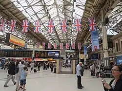 Victoria station concourse. British flags hang from the ceiling.
