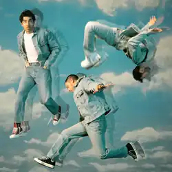 The cover depicts the three brothers wearing denim clothes while jumping and flipping in different directions, with a blue sky with white clouds in the background.