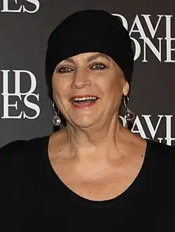 Headshot of a middle-aged, white woman with blue eyes, wearing a black head covering and dress.