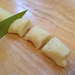 Dough is rolled into long thick round strands, which are cut into pieces.