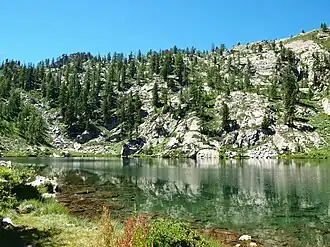 A body of water with rocky mountains in the back.